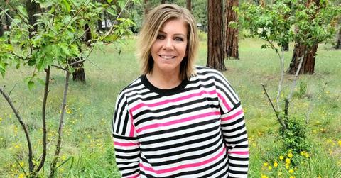 Meri Brown smiles and poses outside in a black, white, and pink LuLaRoe sweater.