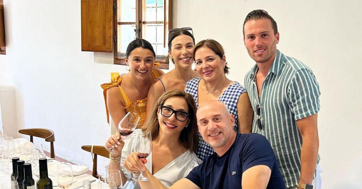 Linda Yaccarino and her husband toasting a glass of wine surrounded by their family in casual outfits.