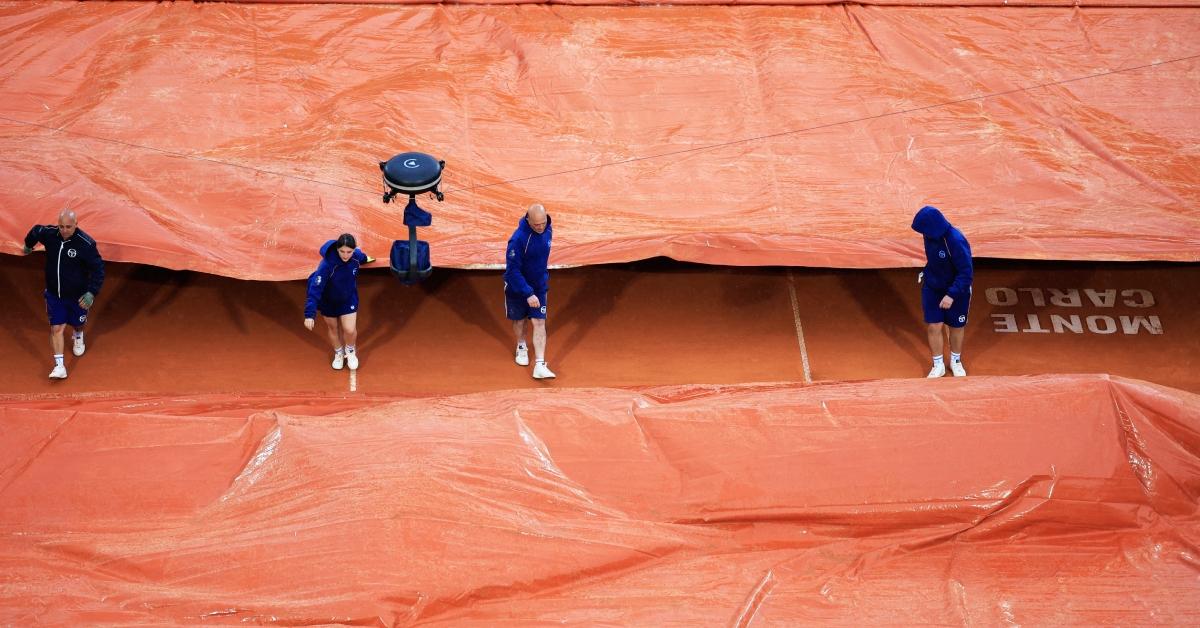 Tournament workers cover a course due to rain in 2024