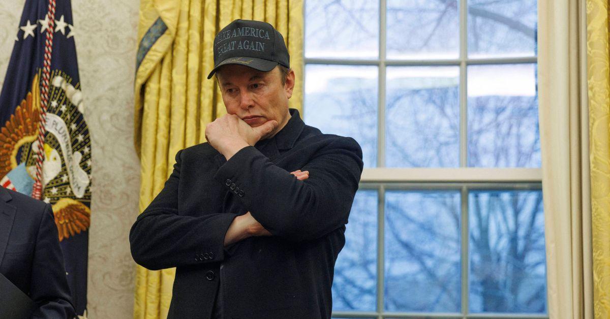 Elon Musk with his hand on his chin in the Oval Office. 