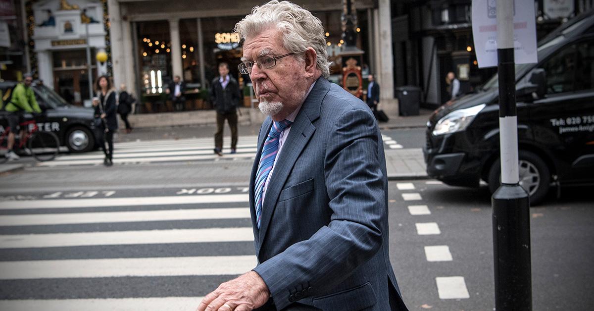 Rolf Harris by a crosswalk in a suit. 