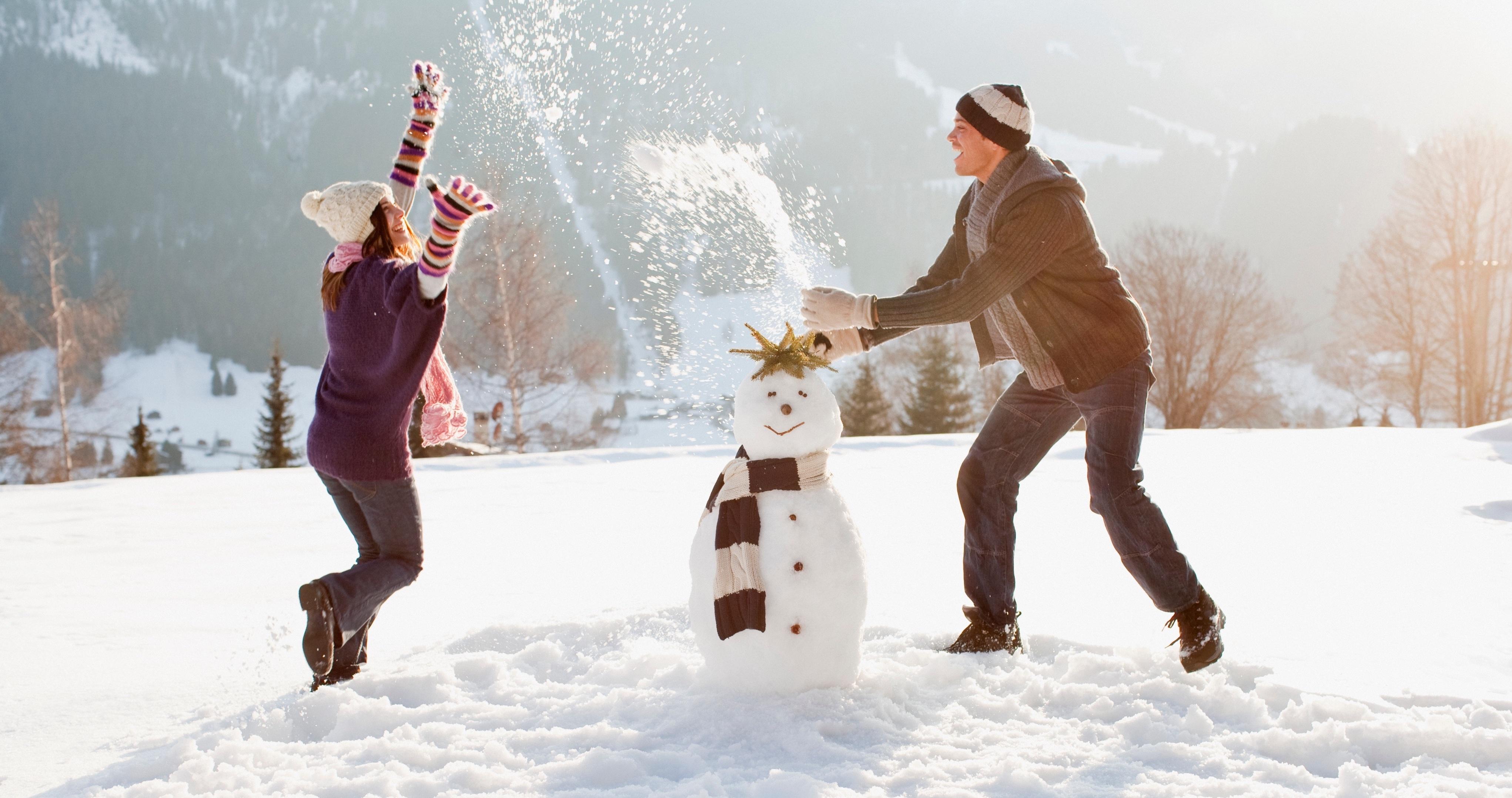 A couple makes a snowman.