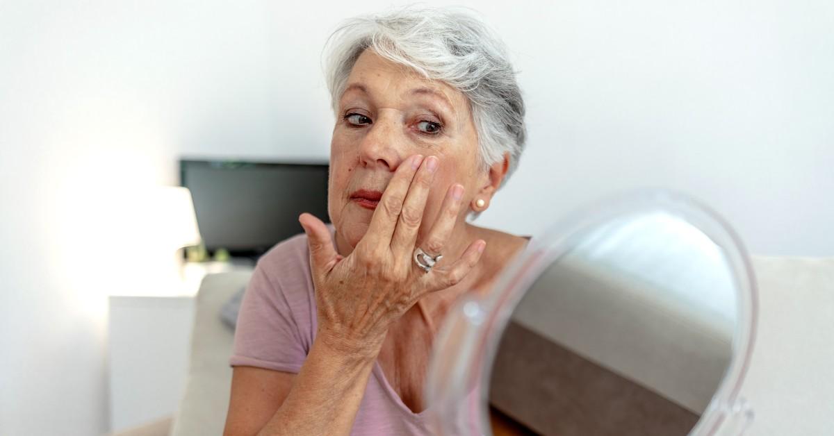 An older woman looking into a mirror.