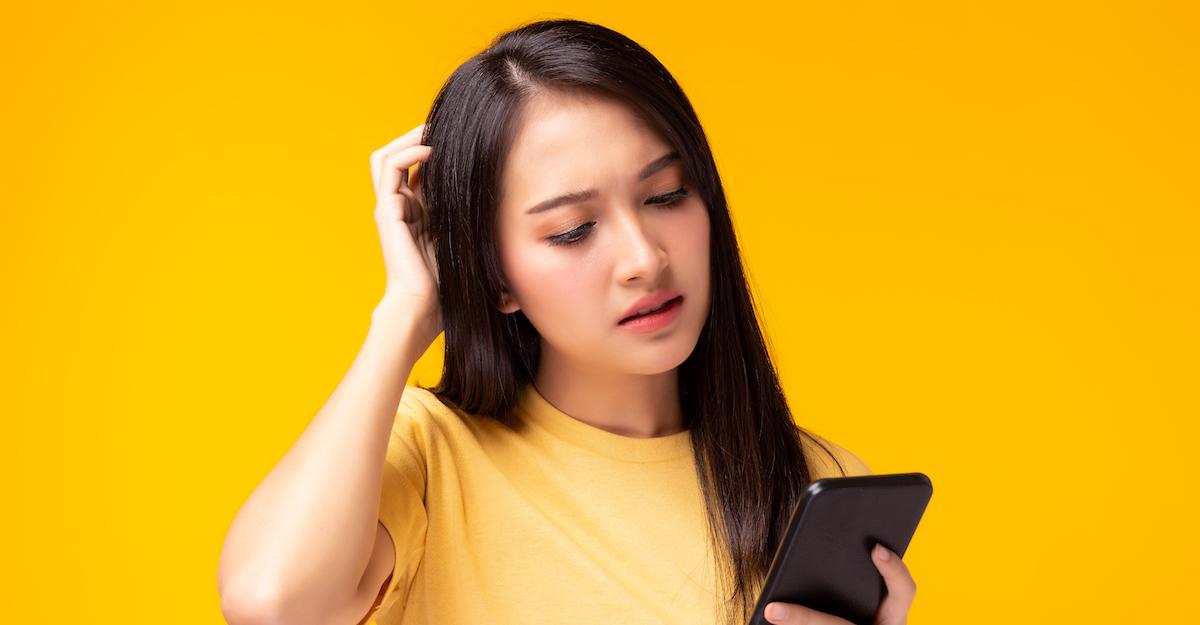 woman looking at her phone confused by Pandora launching randomly