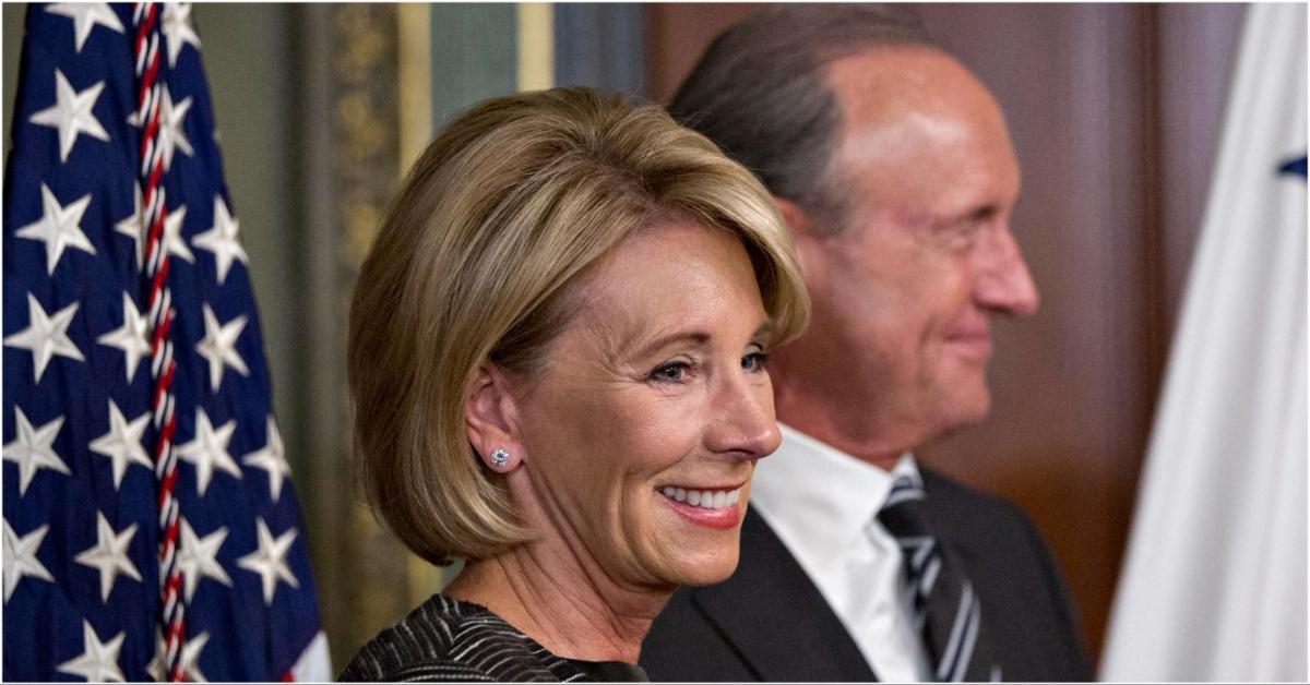 Betsy DeVos smiling during a press conference