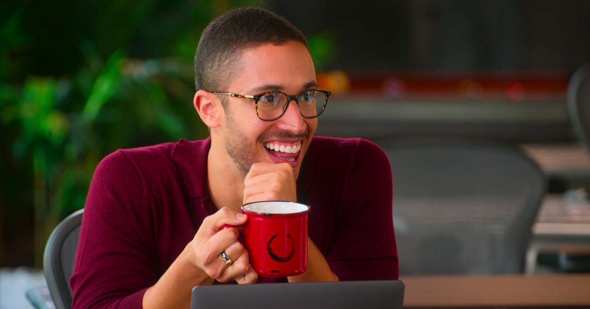 Sean In November 2023, 'Selling the OC' star Sean Palmieri announced he was leaving the Oppenheim Group. Why is that? Here's what we know., sporting glasses and a maroon sweater, smiles while holding a mug in 'Selling the OC.'