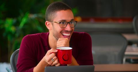 Sean In November 2023, 'Selling the OC' star Sean Palmieri announced he was leaving the Oppenheim Group. Why is that? Here's what we know., sporting glasses and a maroon sweater, smiles while holding a mug in 'Selling the OC.'