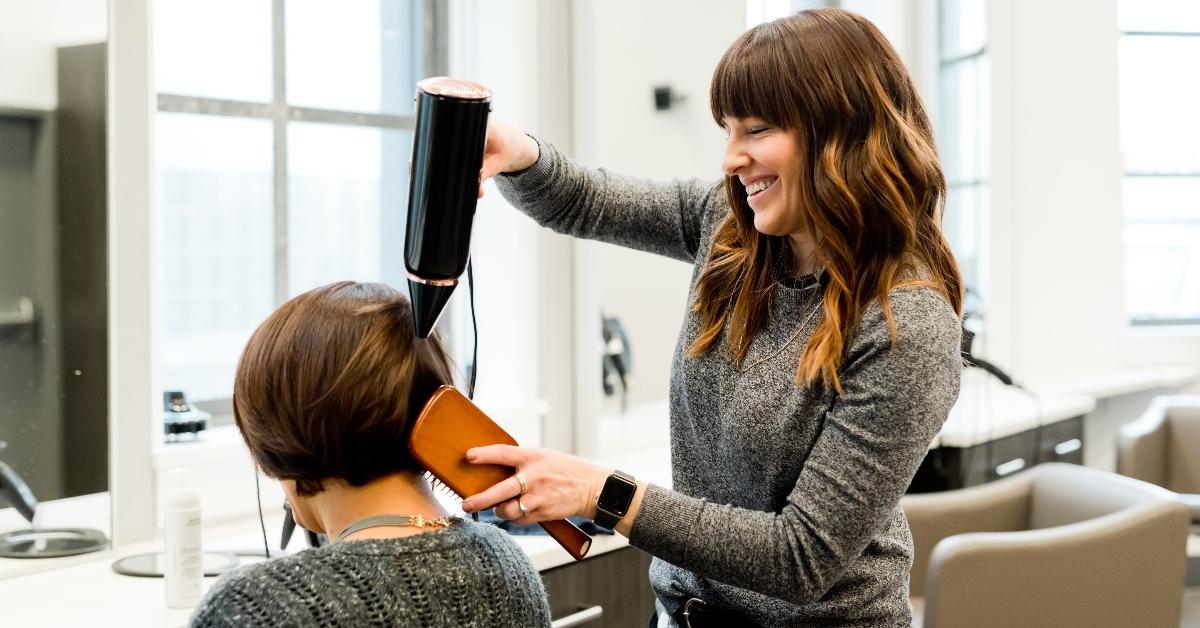 A hairstylist dries hair