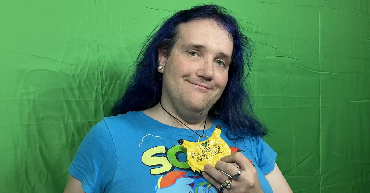 Chris Chan poses in front of a green screen.