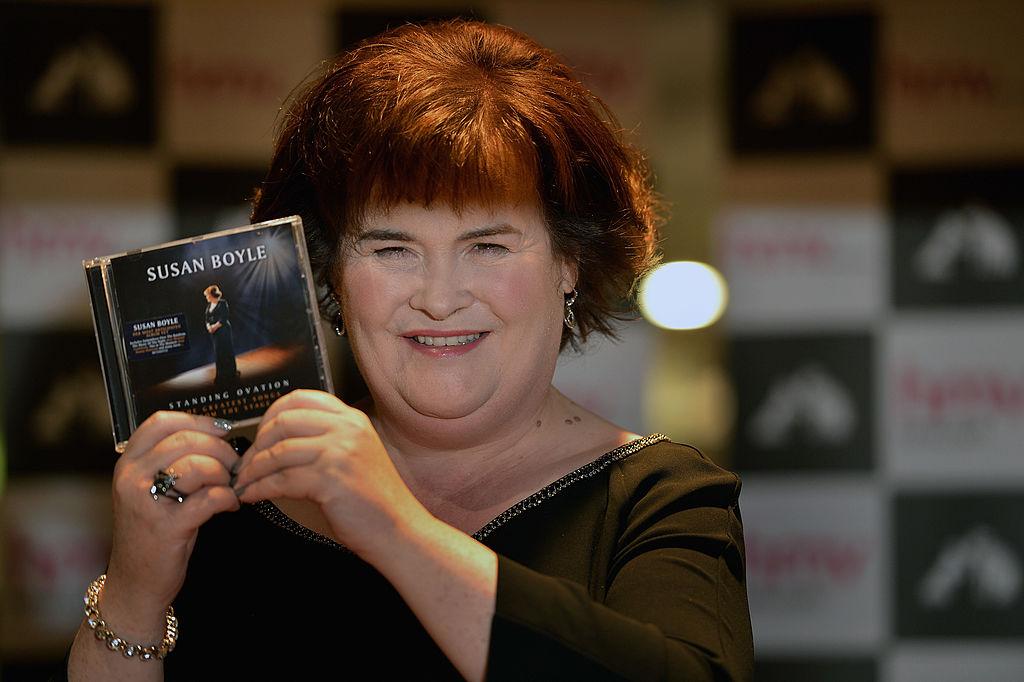 Susan Boyle holding a copy of her CD at a signing event.