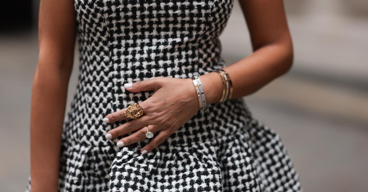 Woman with white nail polish wearing a black and white and tweed dress.