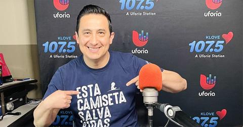 Ysaac Alvarez pointing at his shirt behind a microphone.