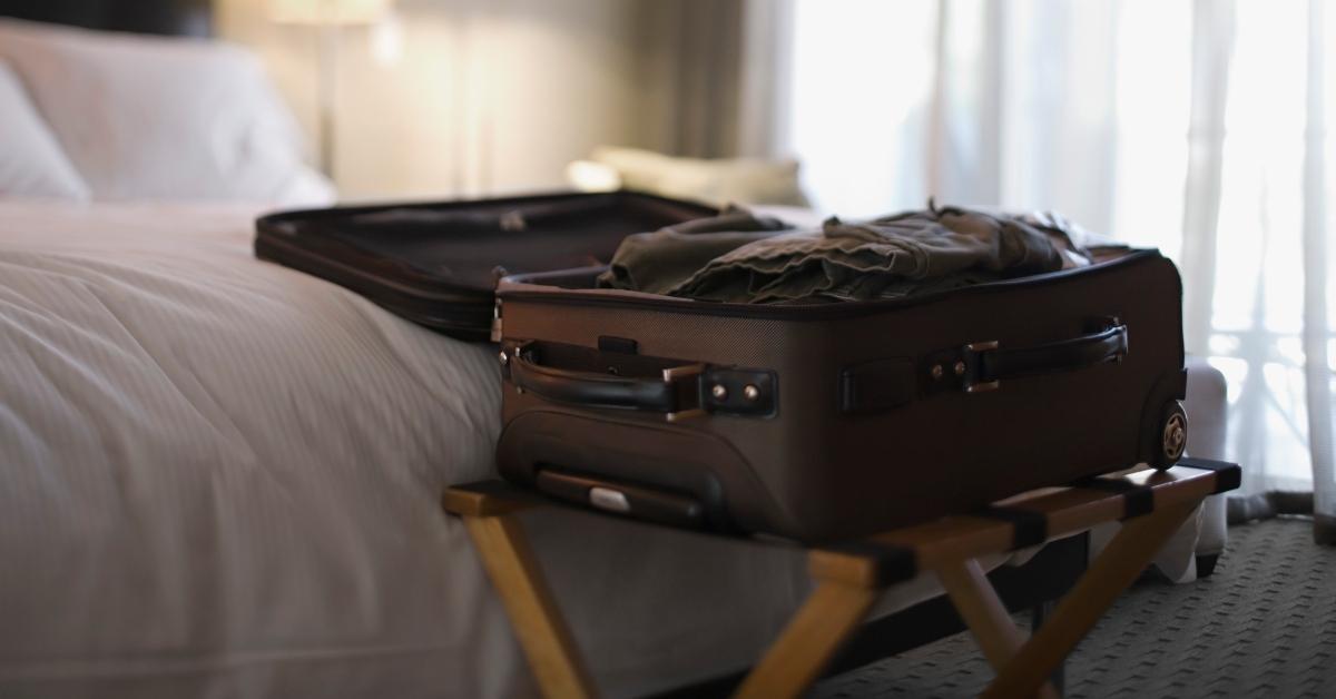 suitcase open by bed in hotel room