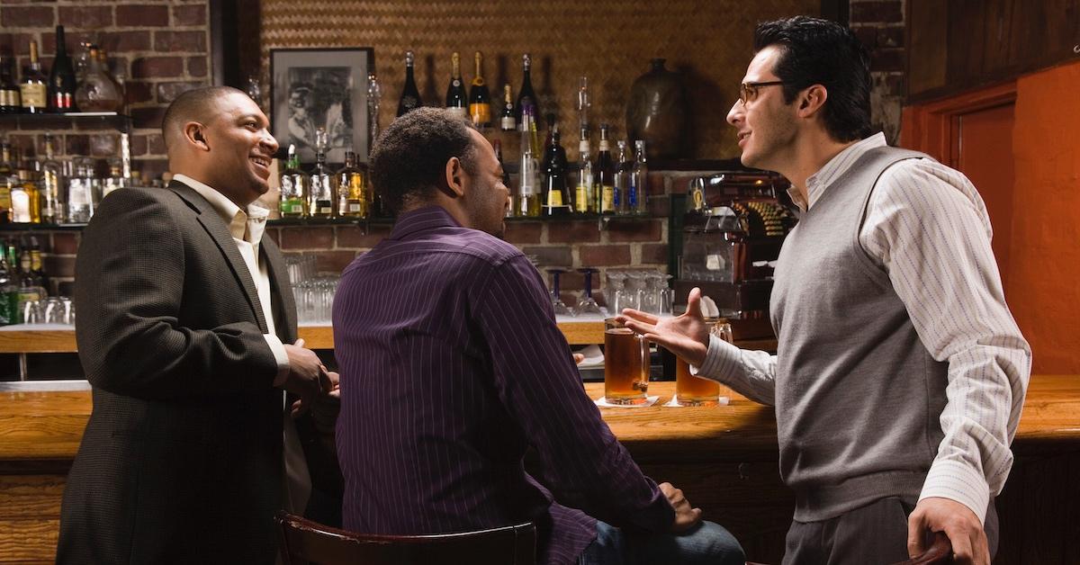 A trio of men hanging out and having drinks at a bar