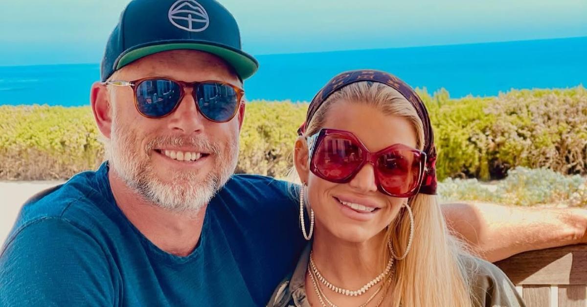 Eric Johnson and Jessica Simpson on a bench in front of an ocean view