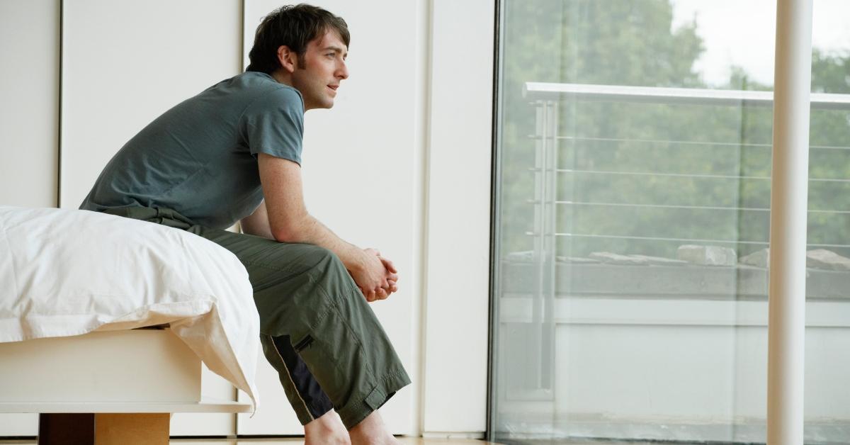 A man looks out his bedroom window. 