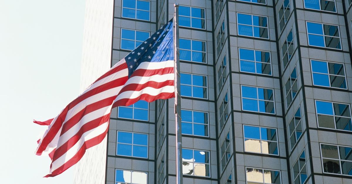 an American flag waving in the wind in front of a building