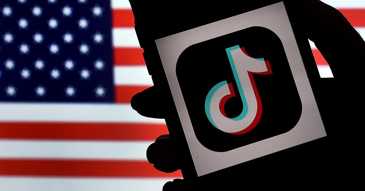 A TikTok logo on a phone with an American flag behind it. 