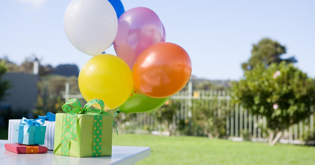 Balloons and birthday gifts on an outdoor table.