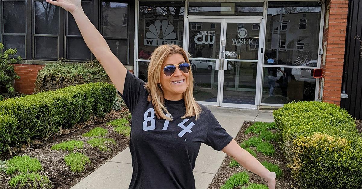 Emily Matson with her arms spread in front of a TV station. 