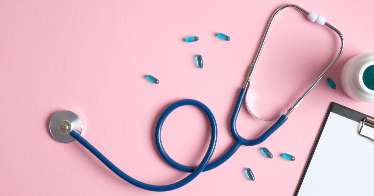 stethoscope and pills on pink backdrop