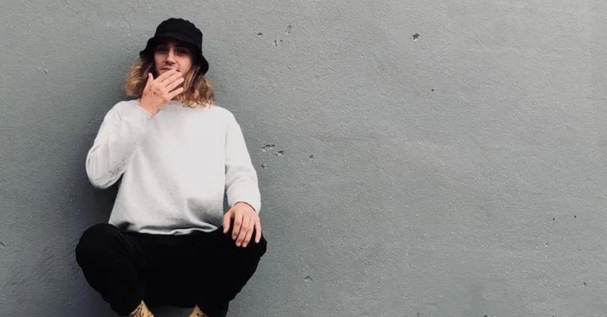 Luke Burland against a gray wall. 