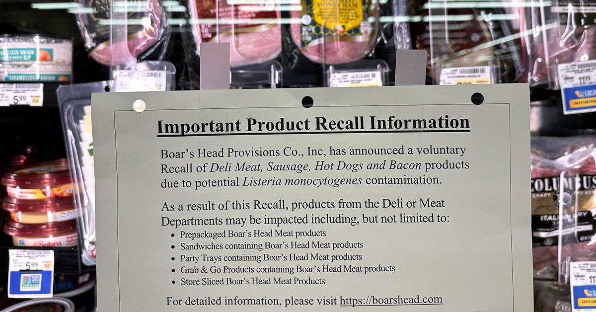 A sign announcing a product recall in front of meat. 