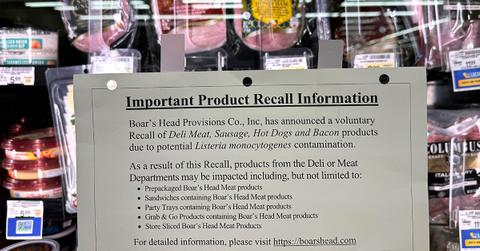 A sign announcing a product recall in front of meat.