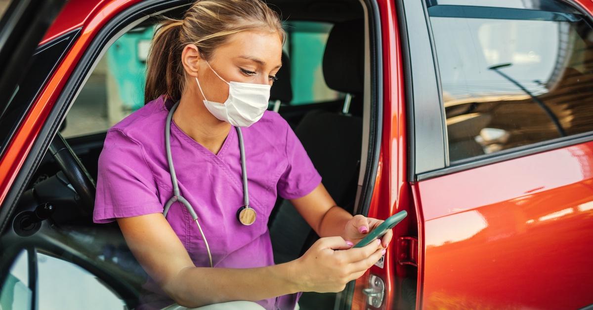 A woman on the phone in the car with her work uniform on