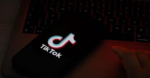 A TikTok logo on a phone screen on a laptop.