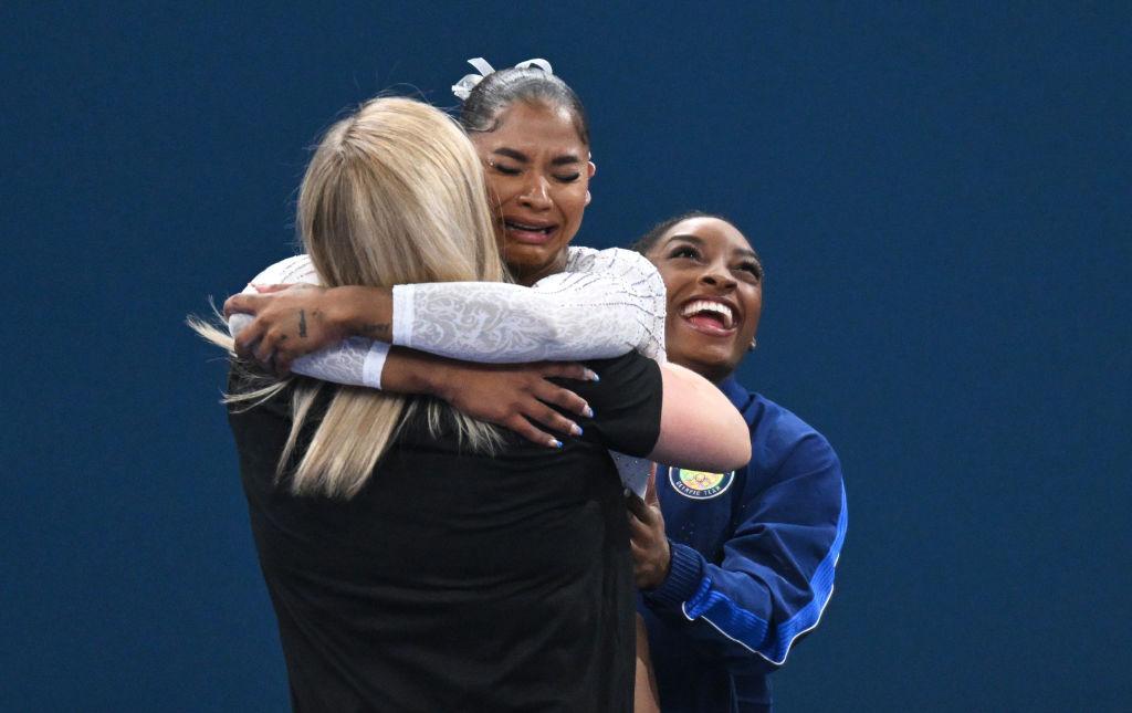 Jordan Chiles hugging her coach and crying after her score was changed while Simone Biles cheers her on.