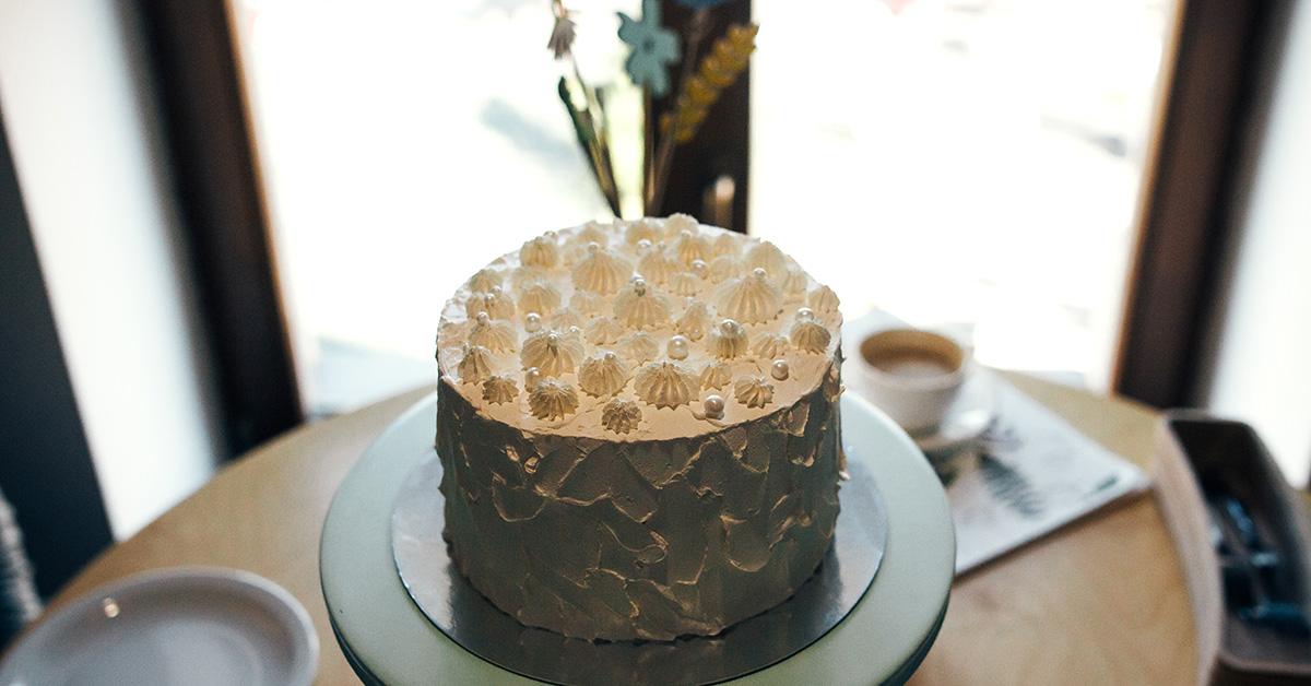 A white cake sitting on a pedestal fully formed. 