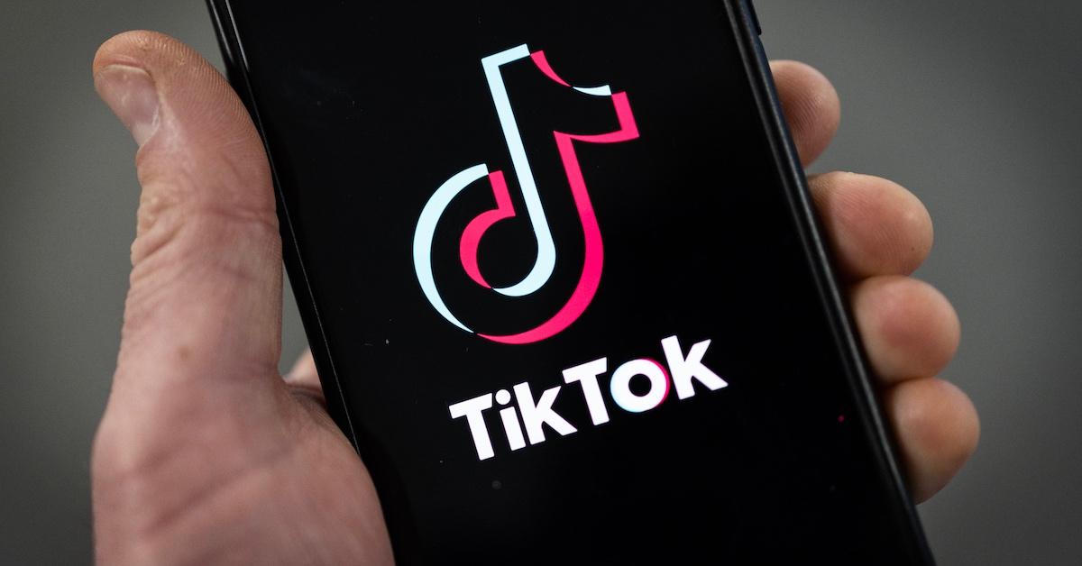 A person holding a smartphone with a TikTok logo displayed.