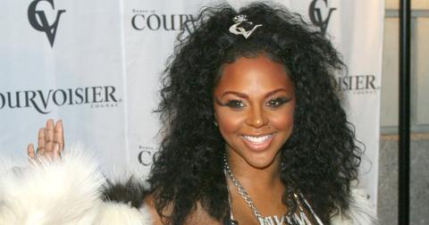 Lil Kim wears dramatic eyelashes and curly hair with a white fur coat and diamond chain at her album release party in 2003.