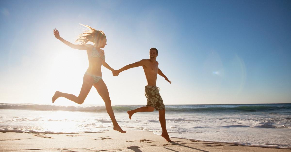 Couple holding hands and running on the beach