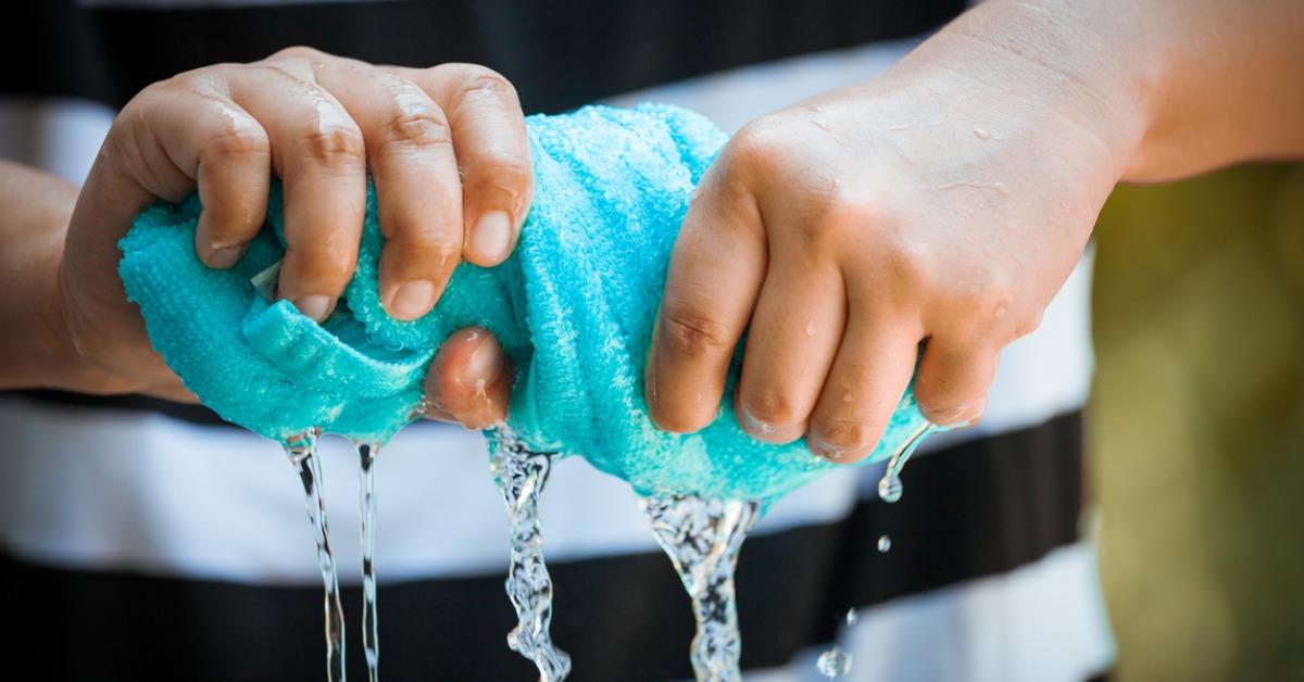 woman hands squeeze wet blue towel and water drop picture id