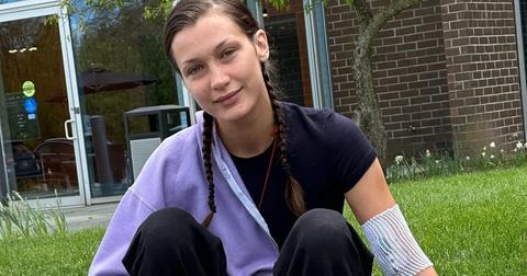 Bella Hadid sitting in the grass with a bandage on her arm