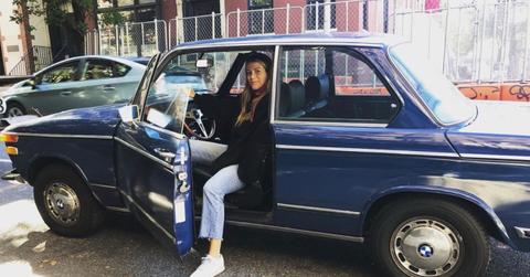 Still shot of Mae sitting in a vintage vehicle