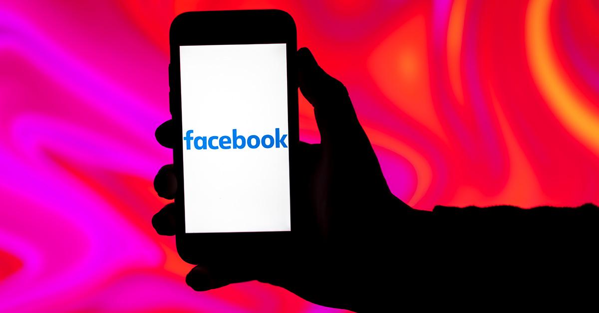 Facebook logo on a phone screen with a pink background. 