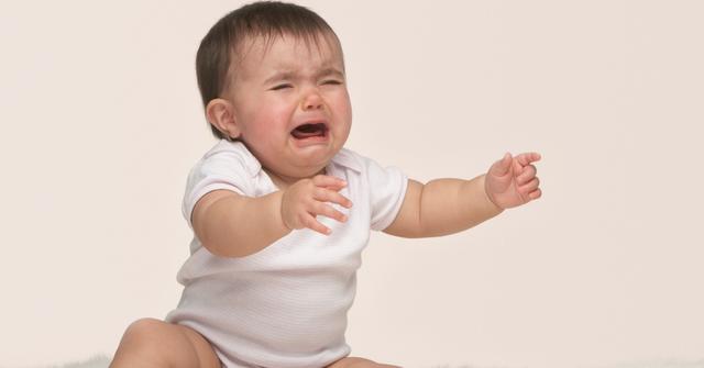 Photograph of baby crying with its arms out.