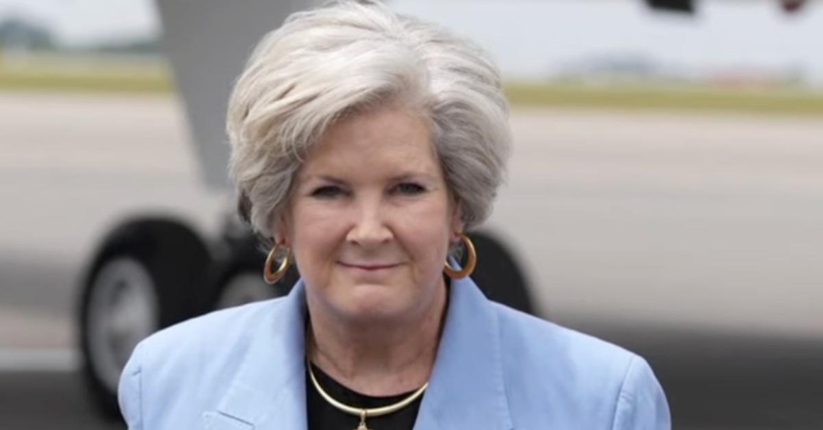 Susie Wiles stands on a tarmac in front of a plane