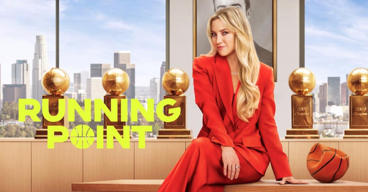 'Running Point' key art featuring Kate Hudson sitting on a desk in a red pant suit.