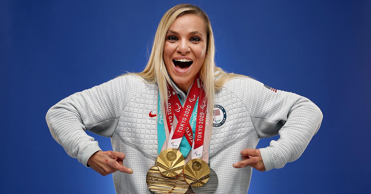 Oksana Masters at the 2022 Olympics pointing at her medals. 