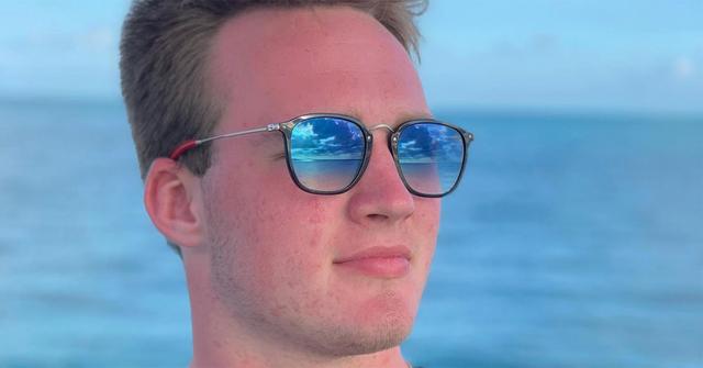 Zak Herbstreit wearing sunglasses near the ocean.