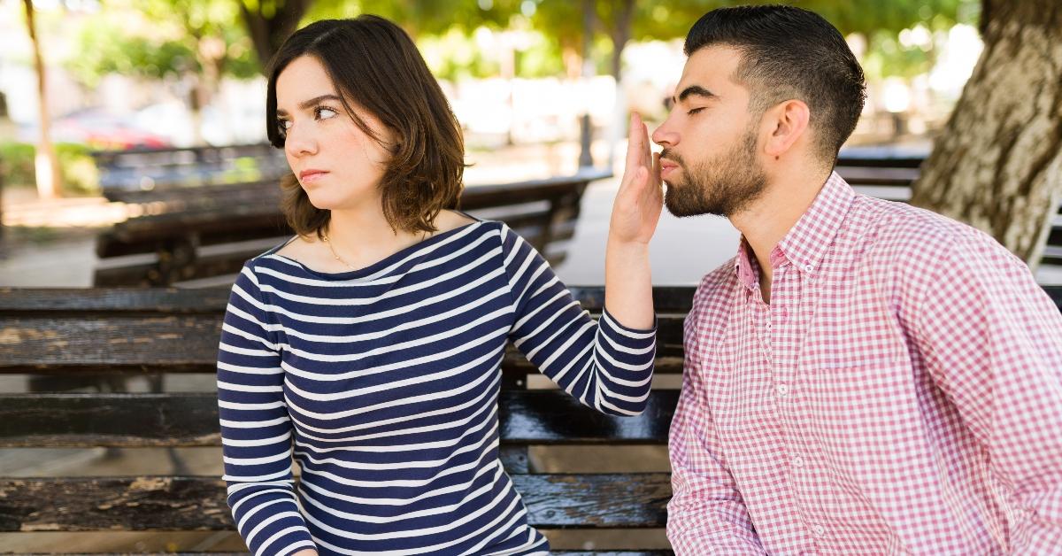 Woman putting her hand up to stop a man from kissing her