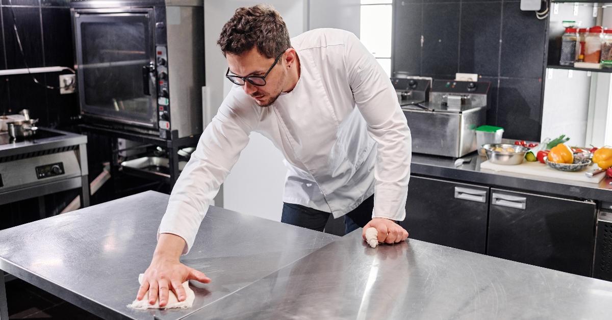 A chef cleaning a restaurant kitchen counter