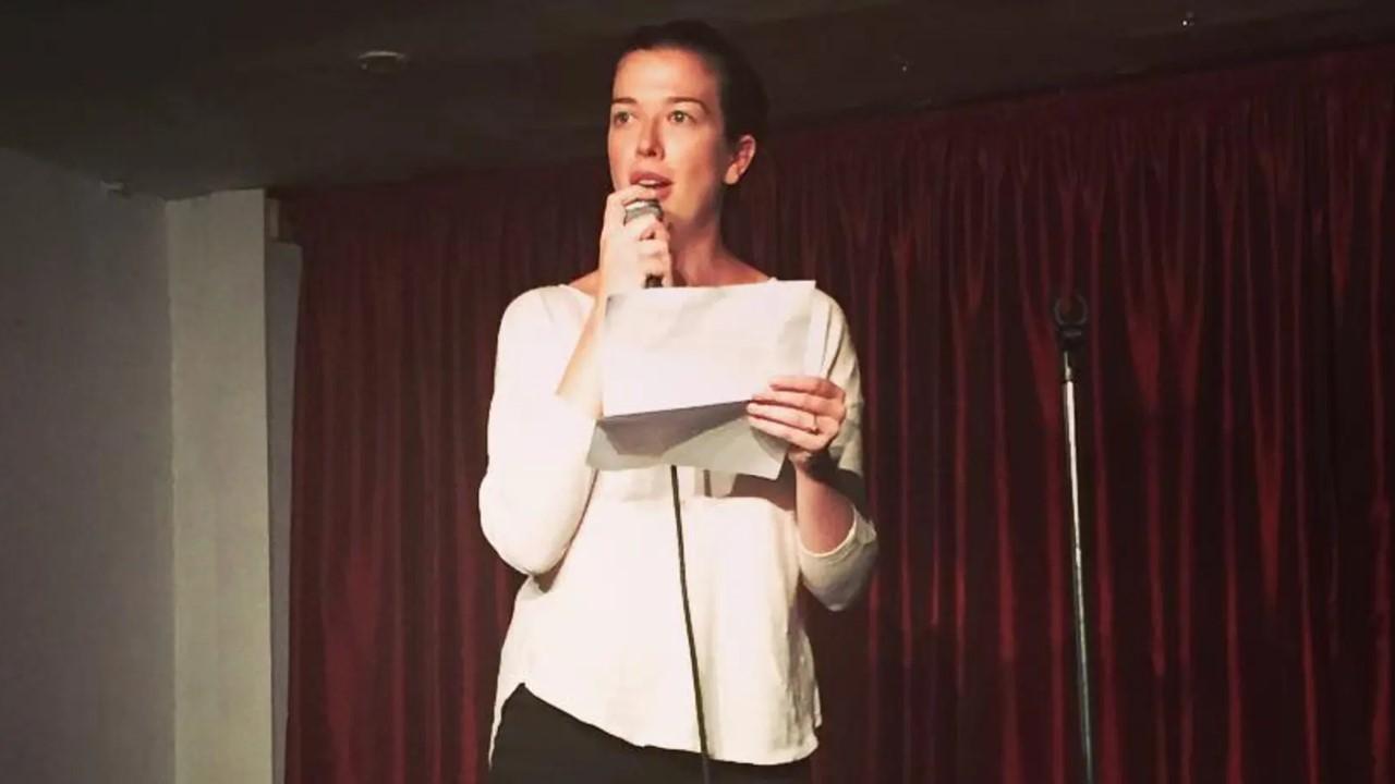 Claire Mulaney in a white shirt performing on stage