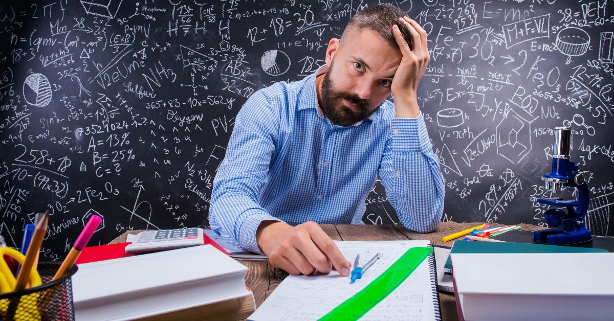 A frustrated teacher sits at his desk