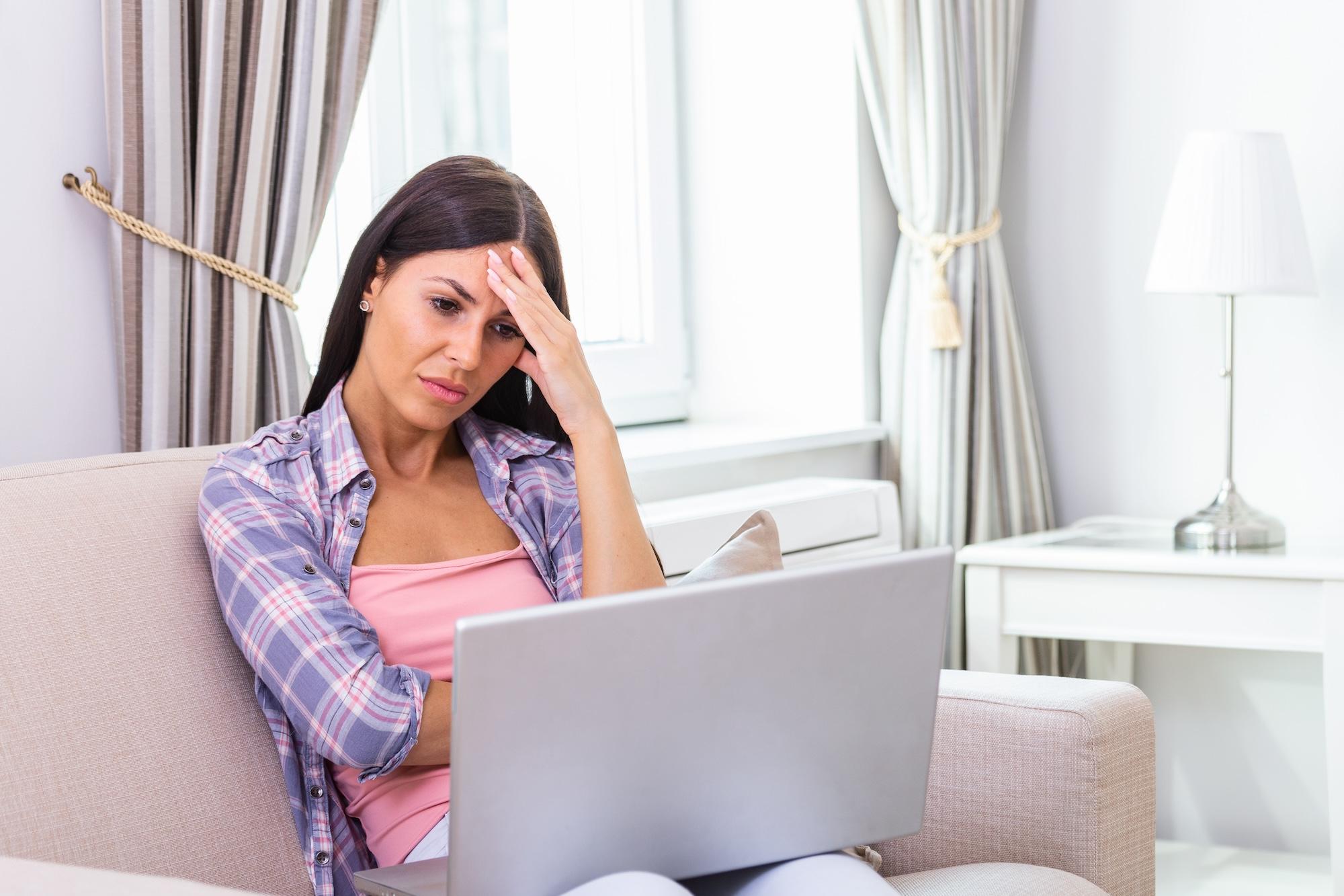 A stressed woman looking at laptop while at home