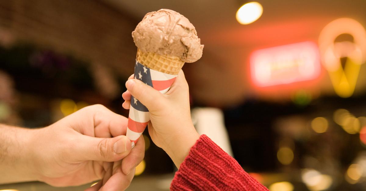 Employee hands over a chocolate ice cream cone to a customer.